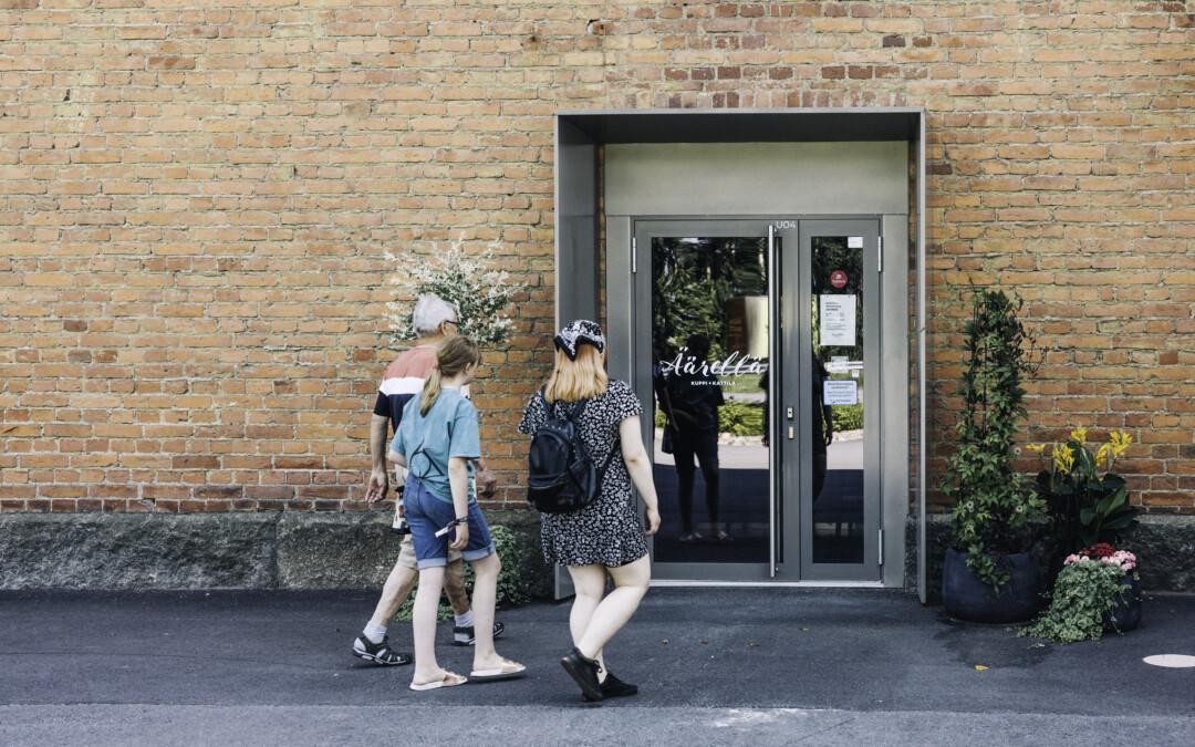 Perhe kävelee sisään tiiliseinäiseen rakennukseen